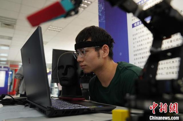 图为参观者体验脑控机器人交互设备。王继军 摄