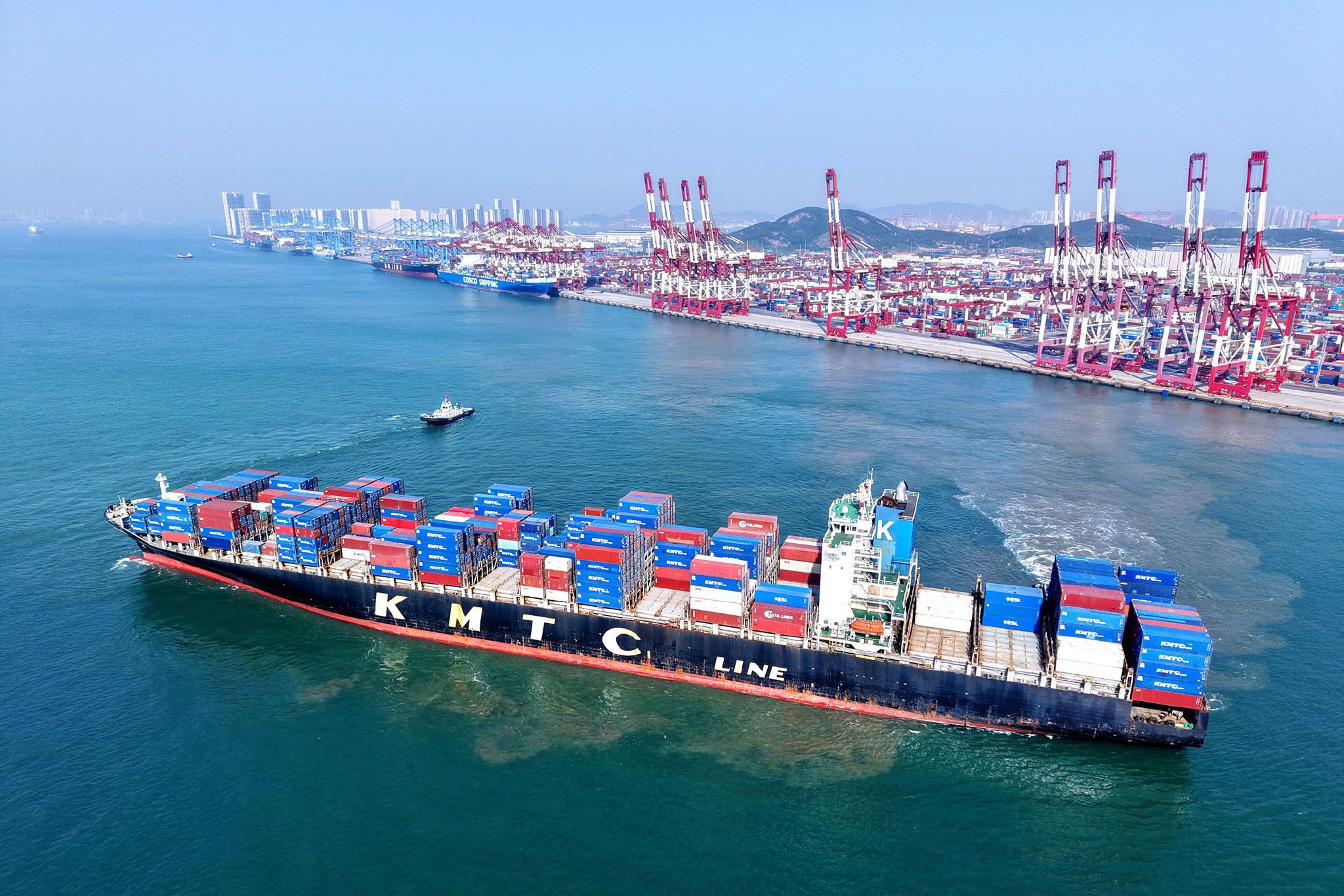 5月19日，山东港口青岛港，装载外贸集装箱的货轮驶出港口（无人机照片）。　新华社发（俞方平　摄）