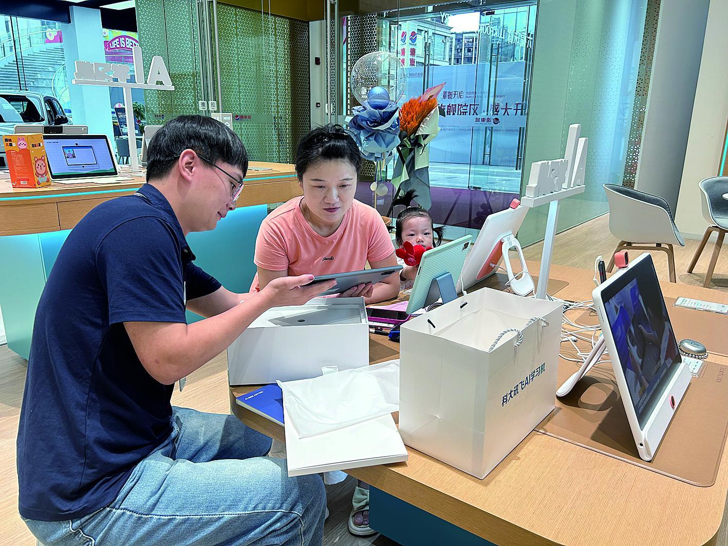 重庆江北观音桥远东城，家长在工作人员指导下体验讯飞AI学习机。