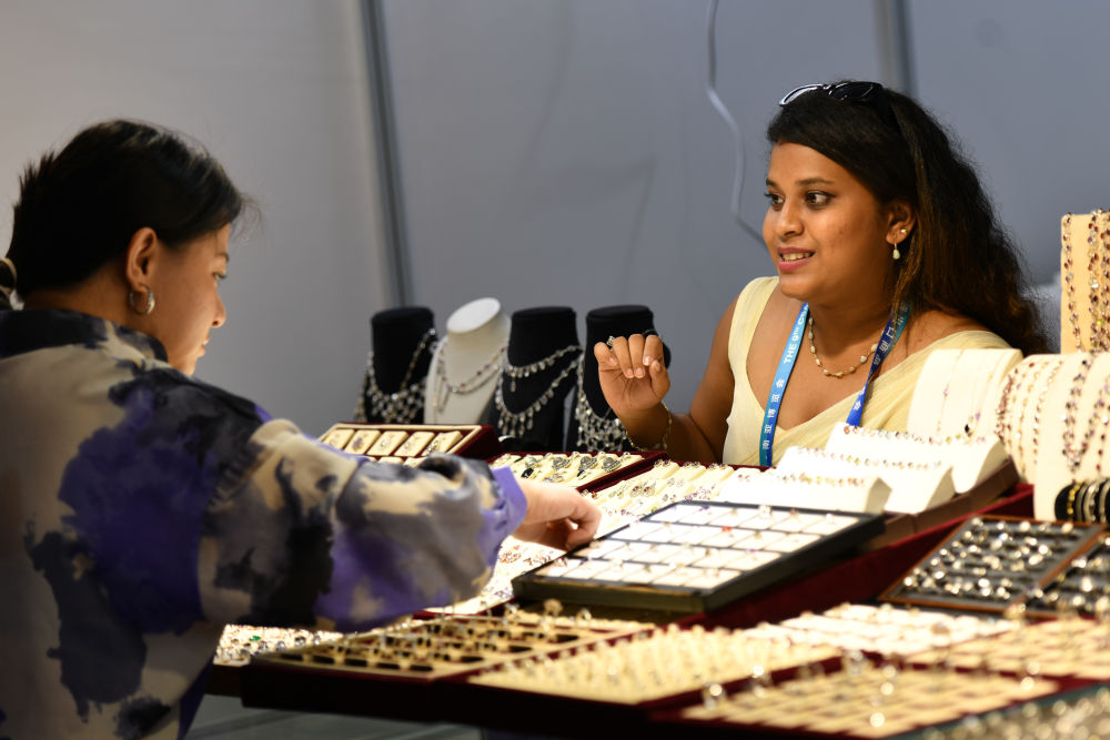 ▲6月19日，斯里兰卡展区的展商向顾客推介特色饰品。新华社发（彭奕凯 摄）