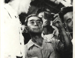 1958年7月，周恩来总理来上钢一厂视察并在平炉车间参加劳动，图为总理在看炉内钢水。（宝山区档案馆馆藏）