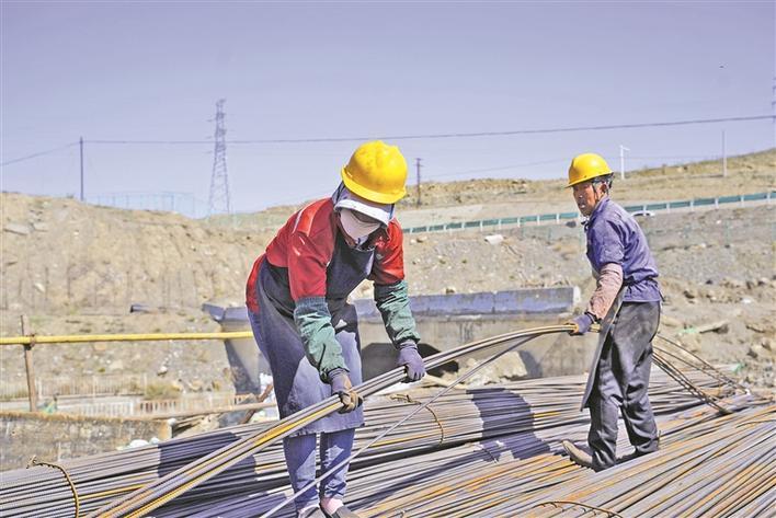 工人在十二师一○四团森朗酒店项目建设现场搬运钢筋