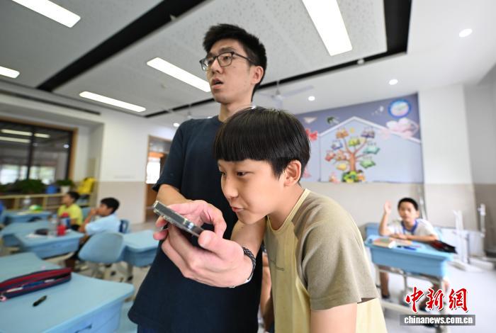 　　7月31日，小学生通过手机和AI对话。中新社记者 王刚摄