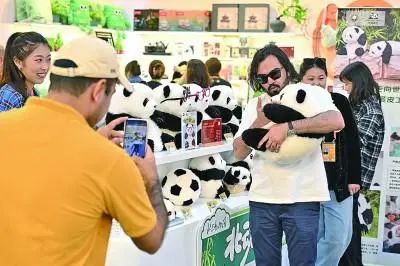 参观者在北京首钢园与大熊猫文创玩偶合影。新华社发