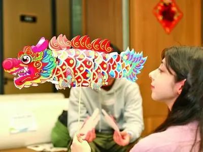 山东青岛，外国留学生在欣赏龙形花灯。新华社发