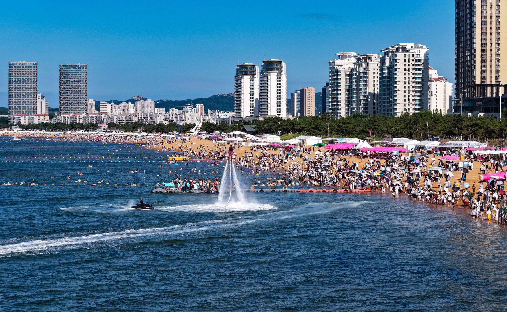 图为大批游客在山东省威海市国际海水浴场戏水纳凉。　新华社发（朱春晓　摄）