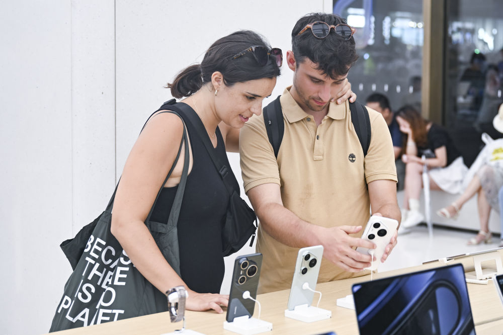 7月17日，两名西班牙游客在位于上海市南京路步行街的华为商店里浏览手机产品。新华社记者 陈浩明 摄