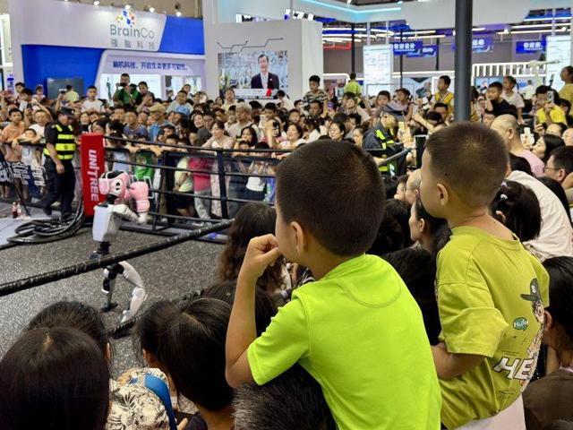图说：智博会上的机器人拳击对战，引来众多家长带着小朋友围观。