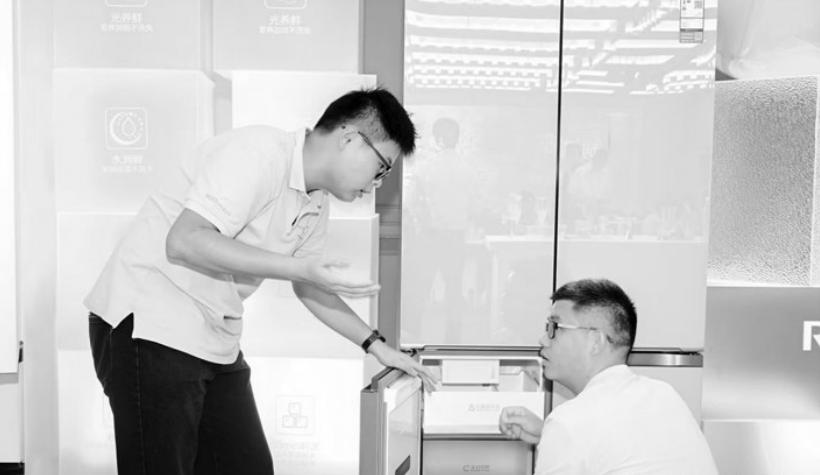 图为店员正在介绍电冰箱。