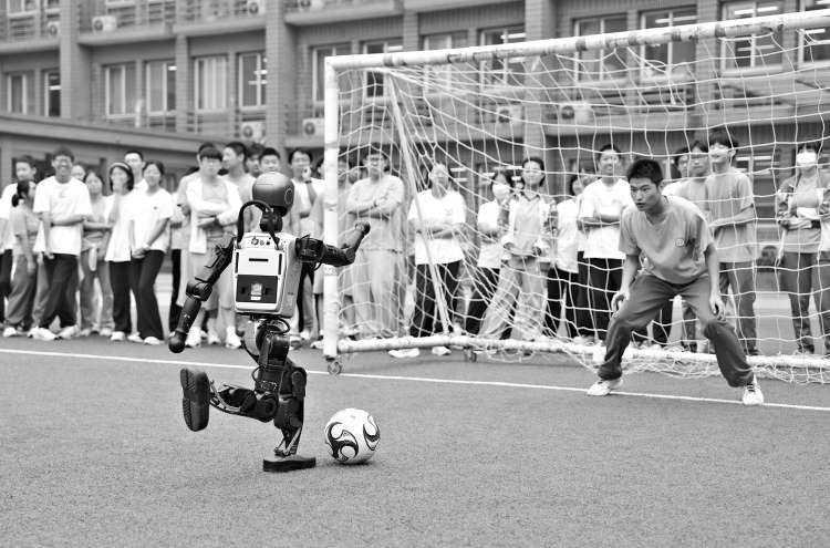 　　在日坛中学操场上，人形智能机器人与学生一起踢足球。本报记者 和冠欣 摄