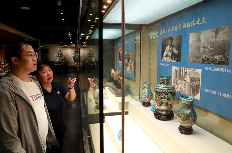 　　工作人员在为观众介绍米振雄的代表作品金玉满堂石榴瓶