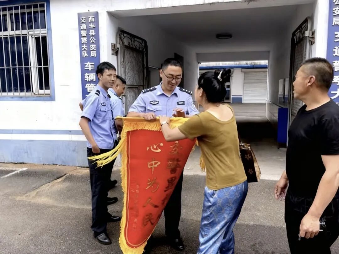 ▲圖為鄭亮(中)及時(shí)破獲交通肇事逃逸案，傷者家屬向鄭亮贈送錦旗。