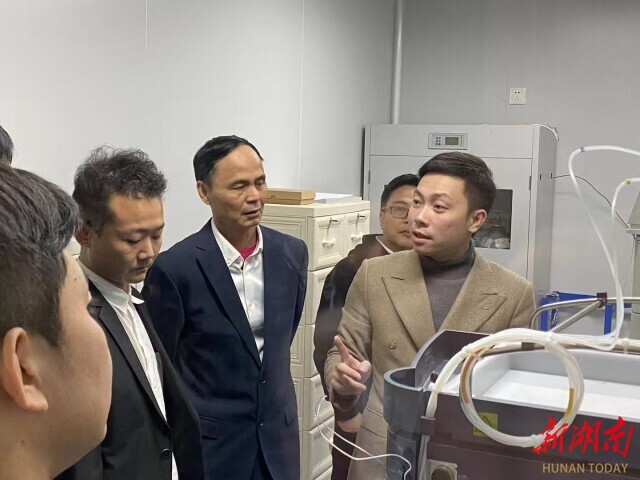 （蒋亦轩（右一）和客户交流公司业务。）