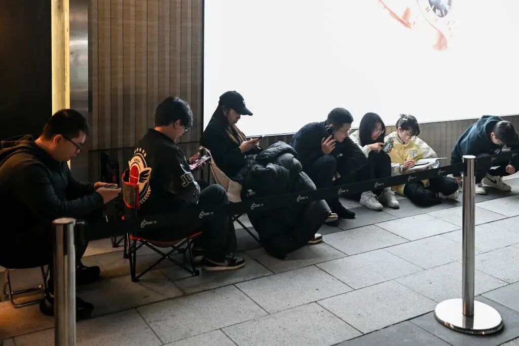 10月24日深夜，上海，排队等候的顾客有的坐在板凳上，有的坐在地上，刷着手机。澎湃新闻记者 朱伟辉 图