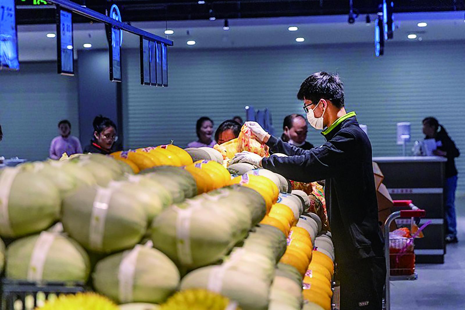 工作人员在调改后的永辉超市生鲜区摆放水果