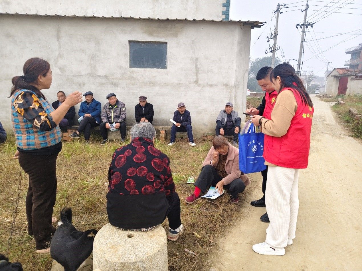 村干部在村民集中聊天的村口发放宣传单,讲解医保政策