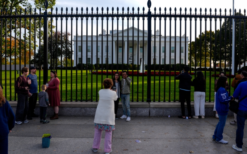▲当地时间2025年11月，美国华盛顿，美国联邦政府“停摆”已进入第二个月，游客在白宫前拍照。图/IC photo