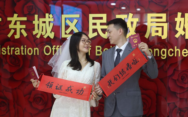 ▲8月10日是七夕节，一对新人拿着结婚证拍照留念。新京报记者 王远征 摄