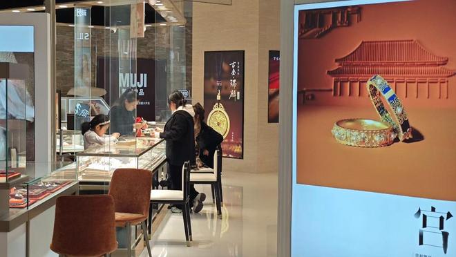 图为消费者在某品牌黄金首饰专柜选购金饰品。