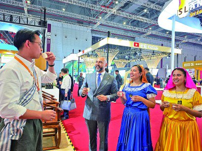     第八届进博会老挝展厅，工作人员邀请萨尔瓦多游客品茶。本报记者 范天培摄/光明图片