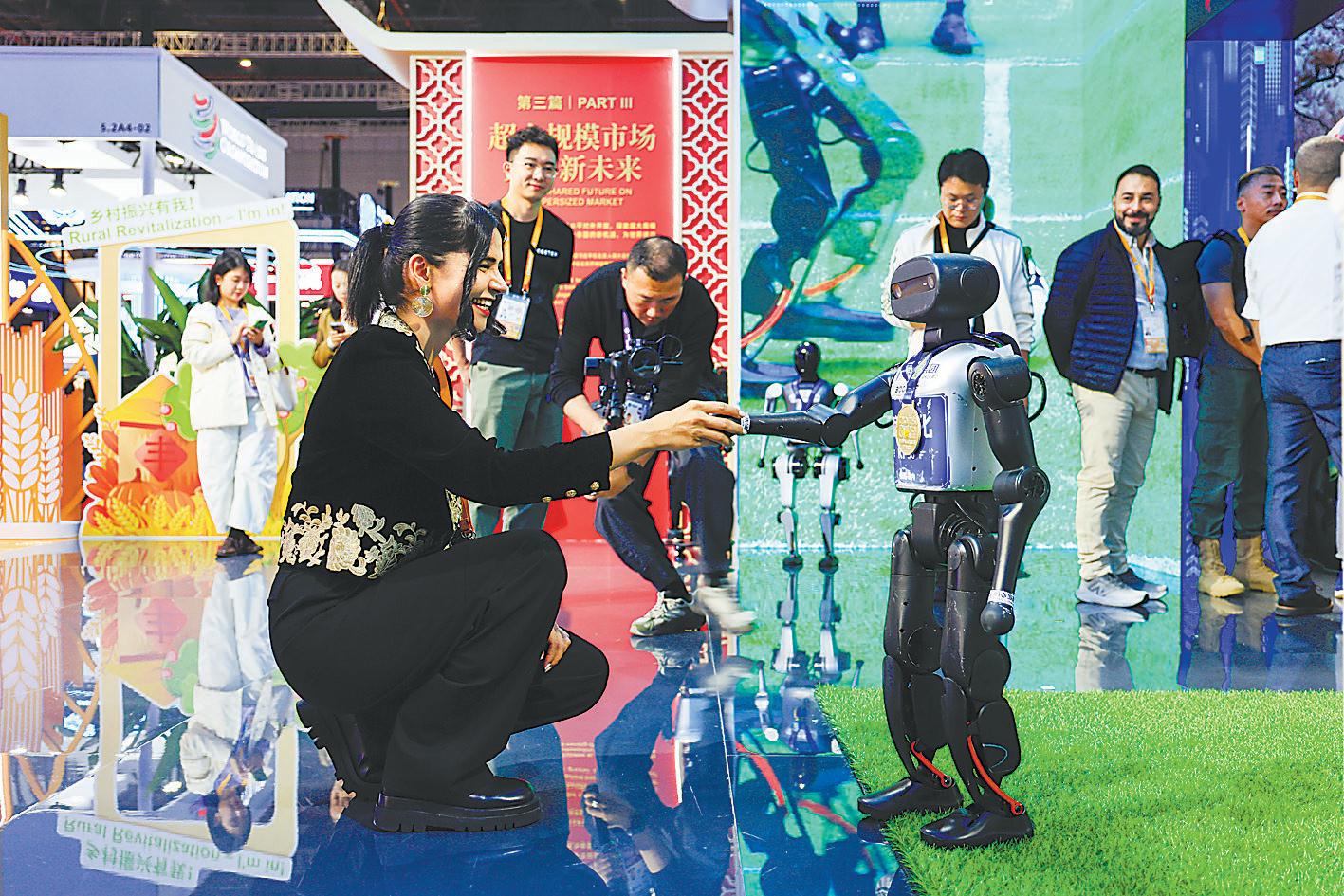 11月5日，进博会国家展中国馆内，一名伊朗参展商和机器人握手。进博会新闻中心供图