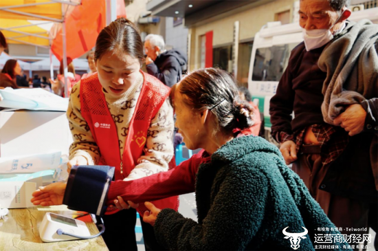 （中国移动工作人员正细心地为老年人测量血压）