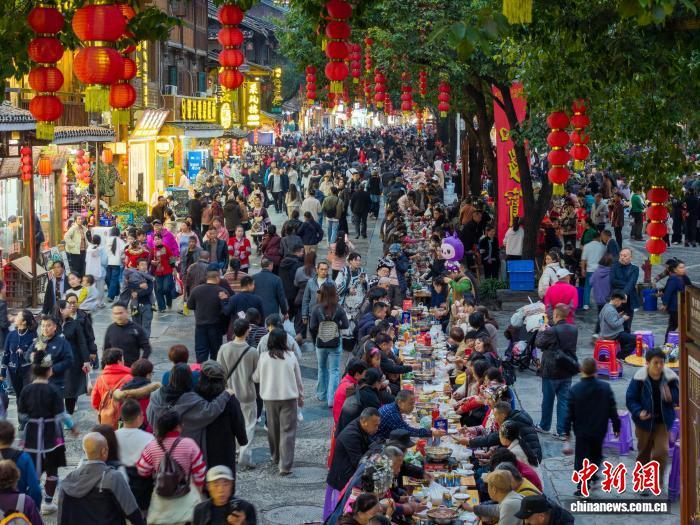 12月20日，贵州省黎平县肇兴侗寨，游客在吃长桌宴。龙建睿摄