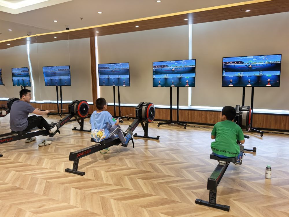 图为运动爱好者在体验智能划船机等设备