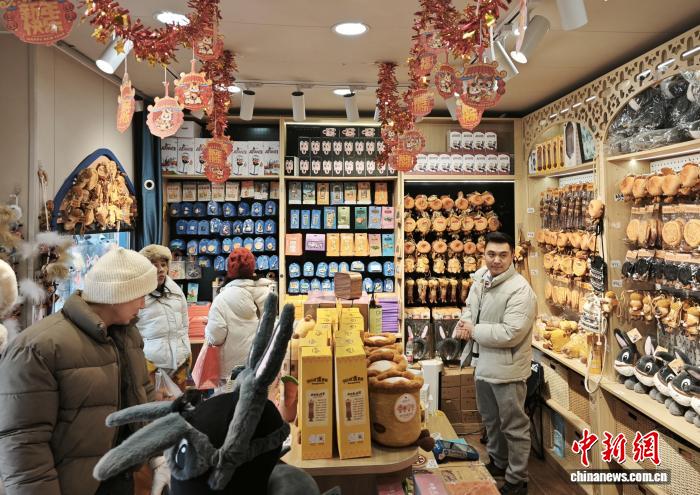 　　1月12日，在位于乌鲁木齐市的新疆国际大巴扎内，游客在阿凡提文创专卖店挑选商品。　苟继鹏 摄