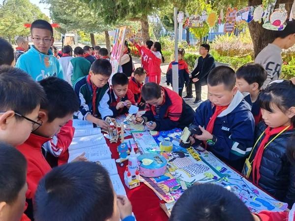 泾川县红河乡九年制学校读书成果展上，学生参观、交流各班展出的作品。泾川县教育供图
