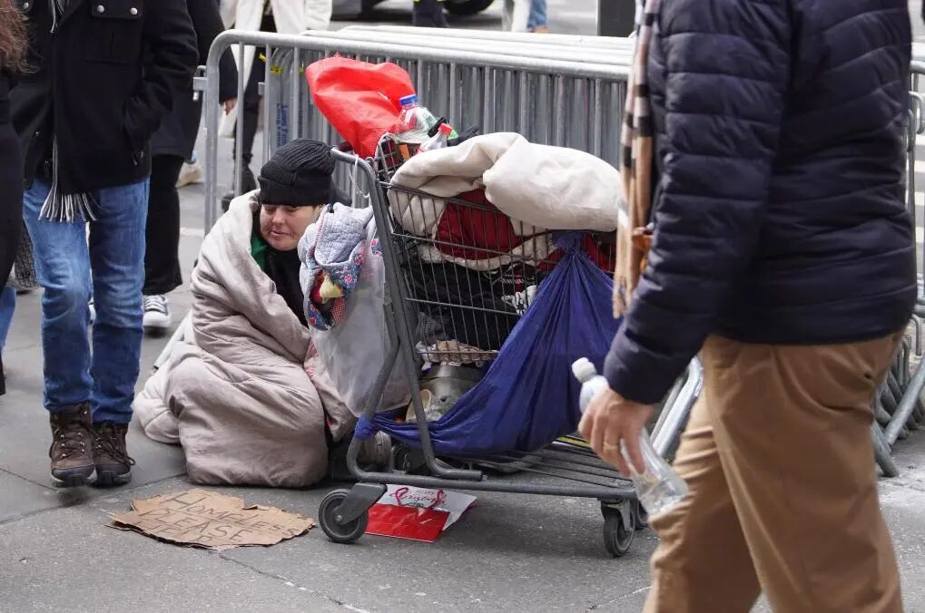 2025年12月31日，在美国纽约街头，无家可归者坐在街边等待帮助。新华社记者 张凤国 摄