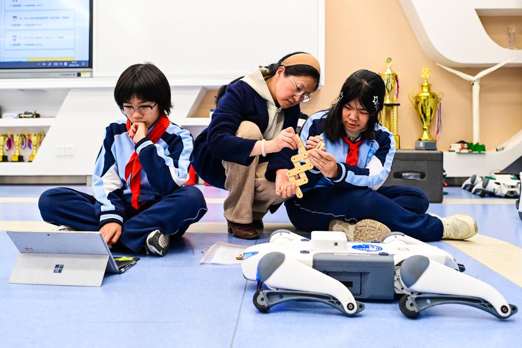 2025年12月2日，杭州市保俶塔实验学校的学生们在人工智能通识课上学习如何给机器狗编程。新华社记者江汉 摄