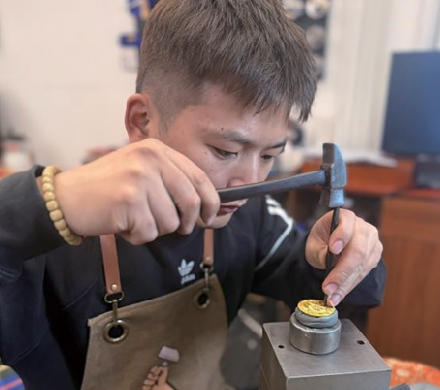 　　图为陈康博在錾刻浮雕牡丹吊牌。