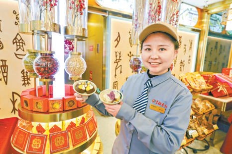 北京稻香村零号寻宝馆店长曹思源展示特色糕点盘纽糕和琵琶糕。本报记者 邓伟 摄