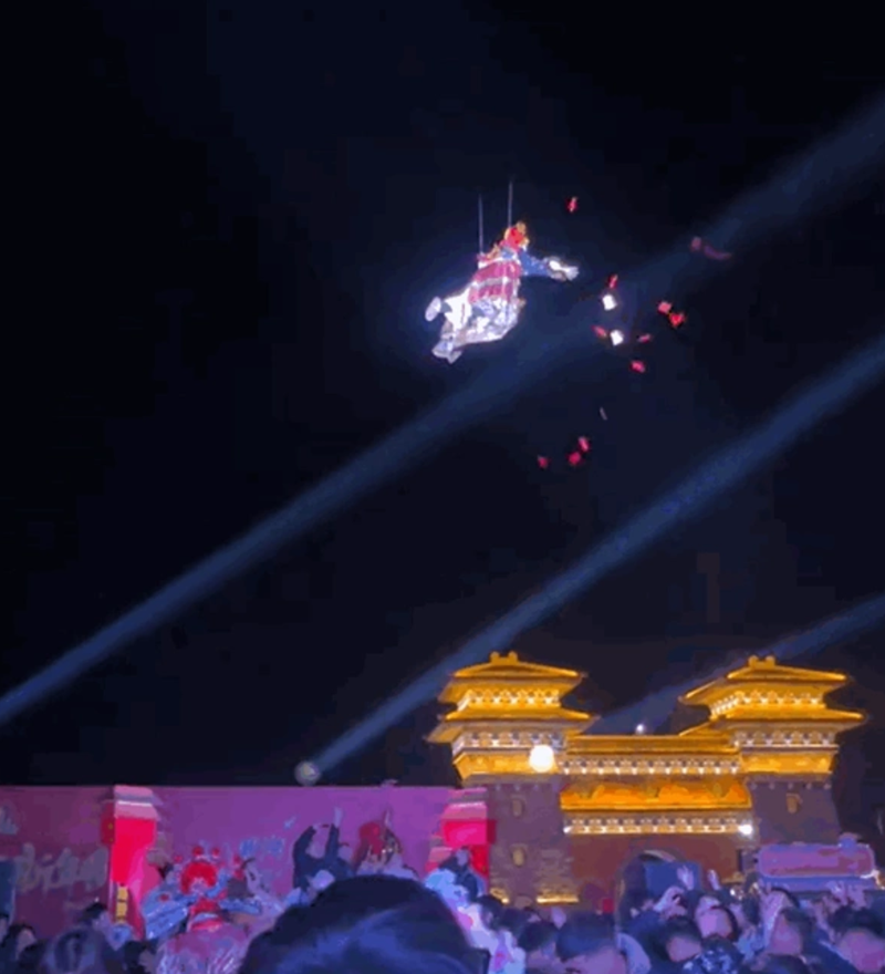 ▲景区一位扮演“财神”的演员在空中撒钱。图/大河报视频截图