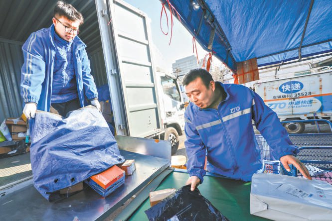 春节期间,在中通快递北京东城区贡院东街网点,都克磊(右)和儿子一起分拣快递,准备配送。 本报记者 邓伟摄