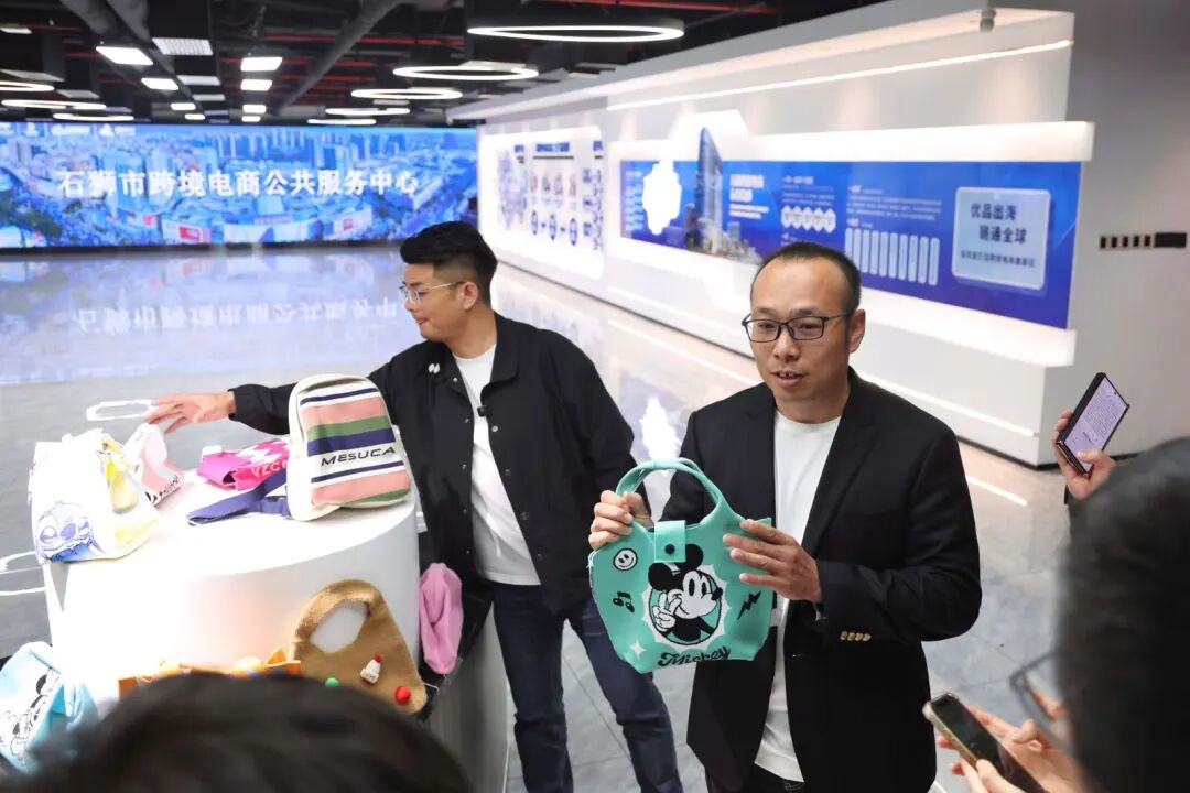 石狮市元德飞织鞋业有限公司王经炜（右）在福建石狮跨境电商公共服务中心介绍飞织包产品 &nbsp;新华社记者 姜克红 摄