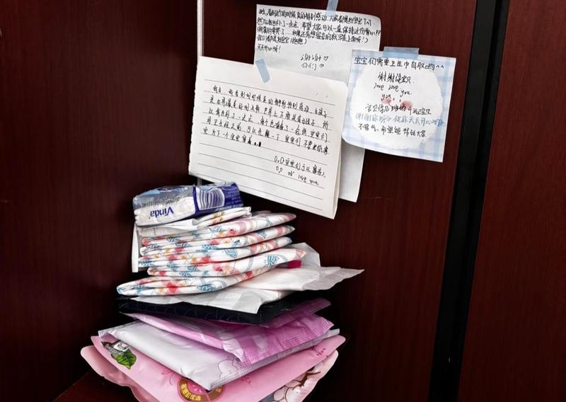 ▲学校初中部女厕所隔间角落里摆放着多款卫生巾，还有同学们留下的暖心便签。图/现代快报