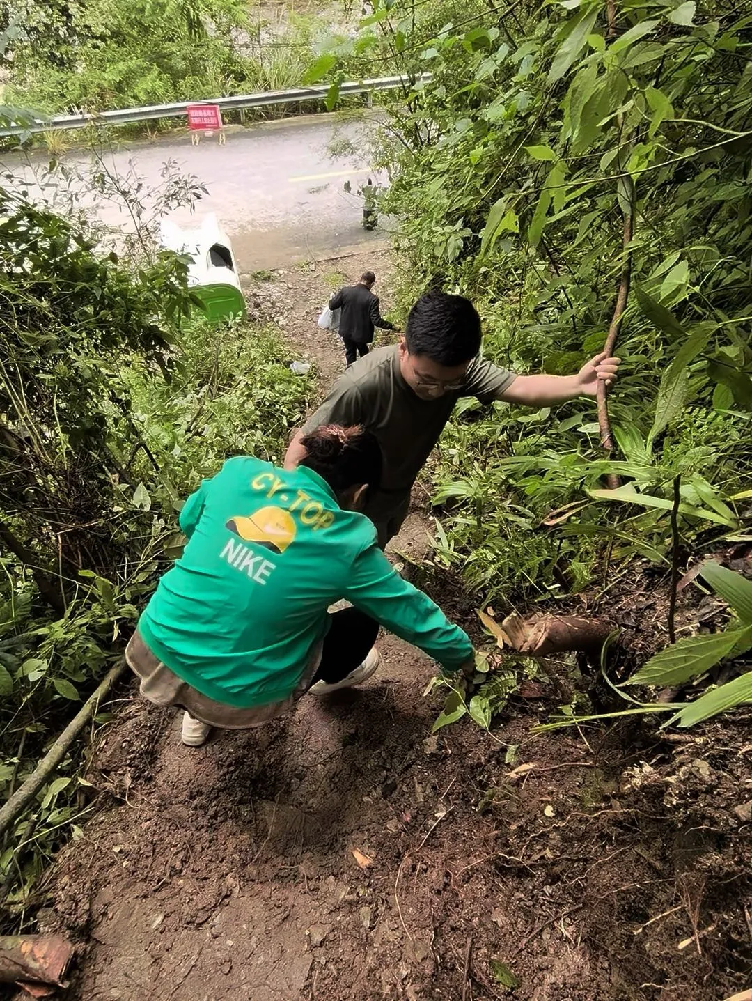 △山路湿滑，唐振邦扶村民走下小路。