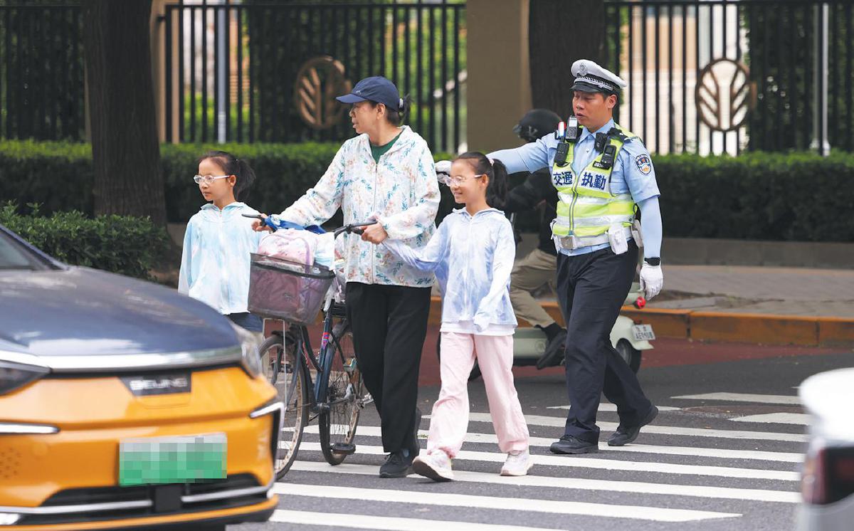 交警示意机动车让行过马路的家长和学生。
