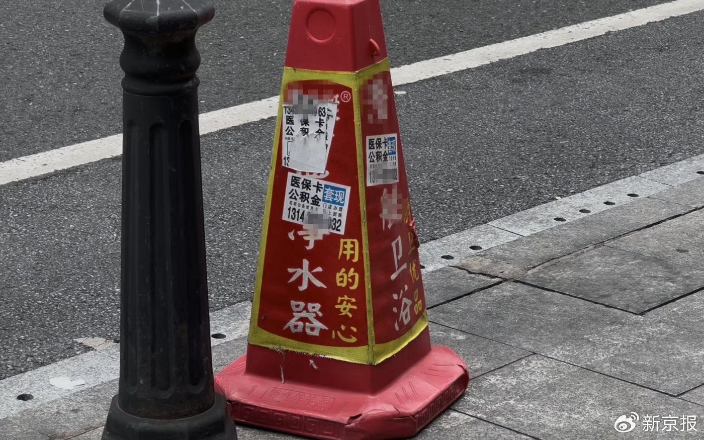 广州越秀区，路边锥桶上贴着多张医保、公积金套现的小广告。 新京报记者 齐少乾 摄