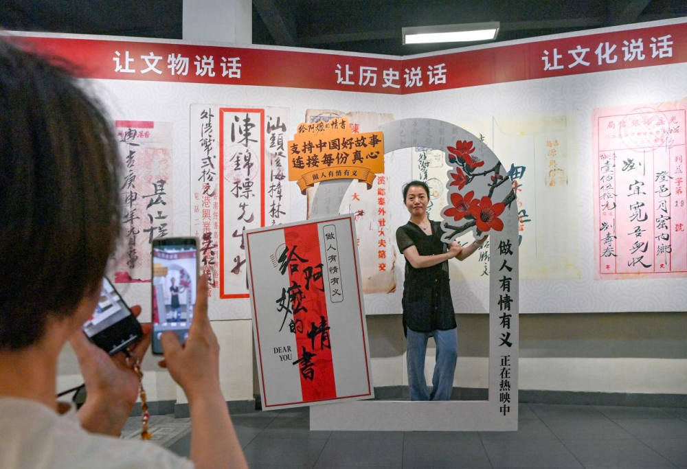 游客在广东省汕头市档案馆侨批分馆（侨批文物馆）内电影打卡点前拍照留念。新华社发
