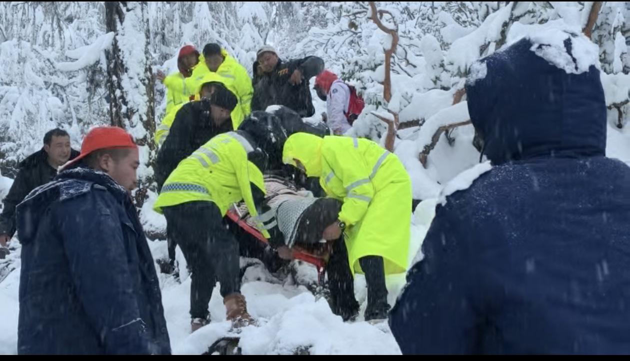 ▲警民在雪中抬着高反男游客下撤