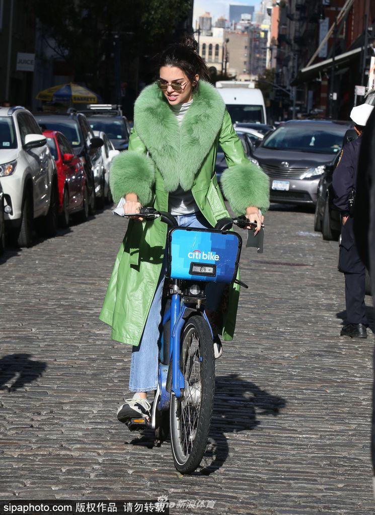 詹娜穿绿色皮草大衣街头骑单车