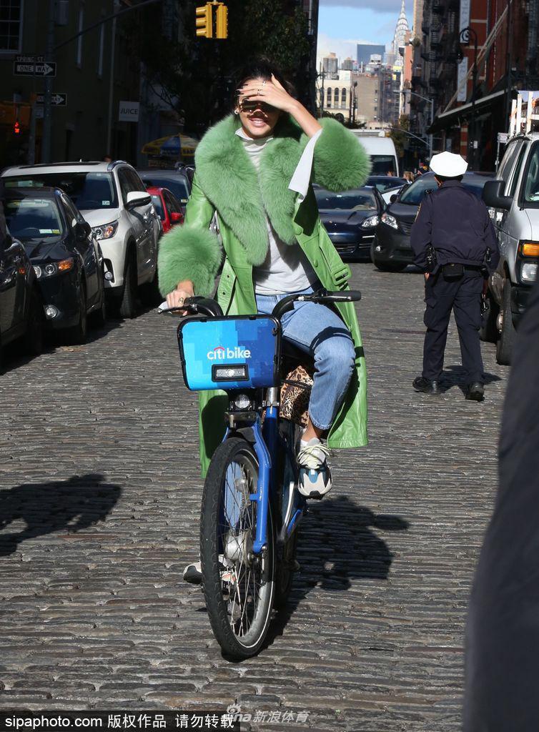 詹娜穿绿色皮草大衣街头骑单车