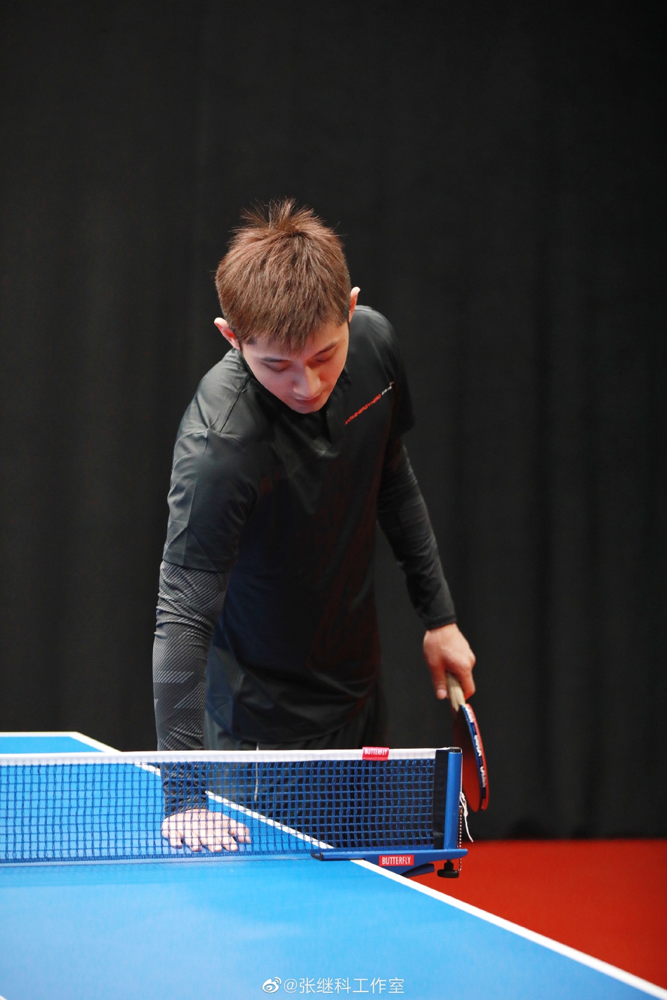 张继科身着黑色运动服打乒乓球
