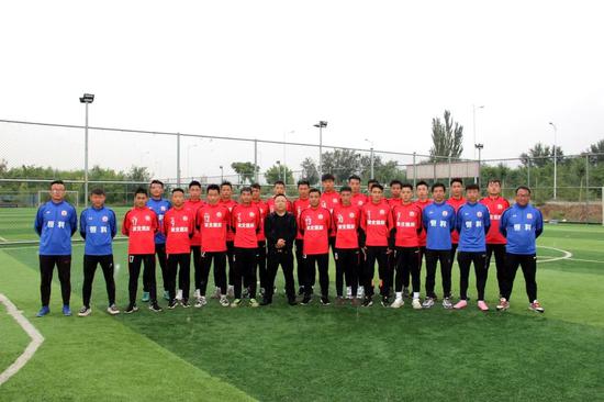 图为黄利锋（前排左7）和俱乐部部分教练员还有U18队员合影。