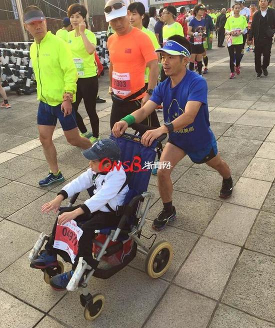 暖父推着脑瘫儿子跑杭马，望将来一起完赛铁人三项。
