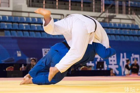 图为男子 100kg级铜牌赛,辽宁选手左荣波(蓝衣)以一个抱单臂背负投