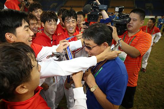 2017全运会U18男足上海 队夺冠后，队员把金牌挂在老帅徐根宝的脖子上。
